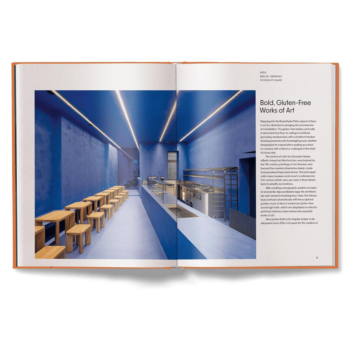 An open architectural design book showing a magazine-style interior layout with a blue modern dining or cafe space, caption text, and the title 'Bold, Gluten-Free Works of Art.'.