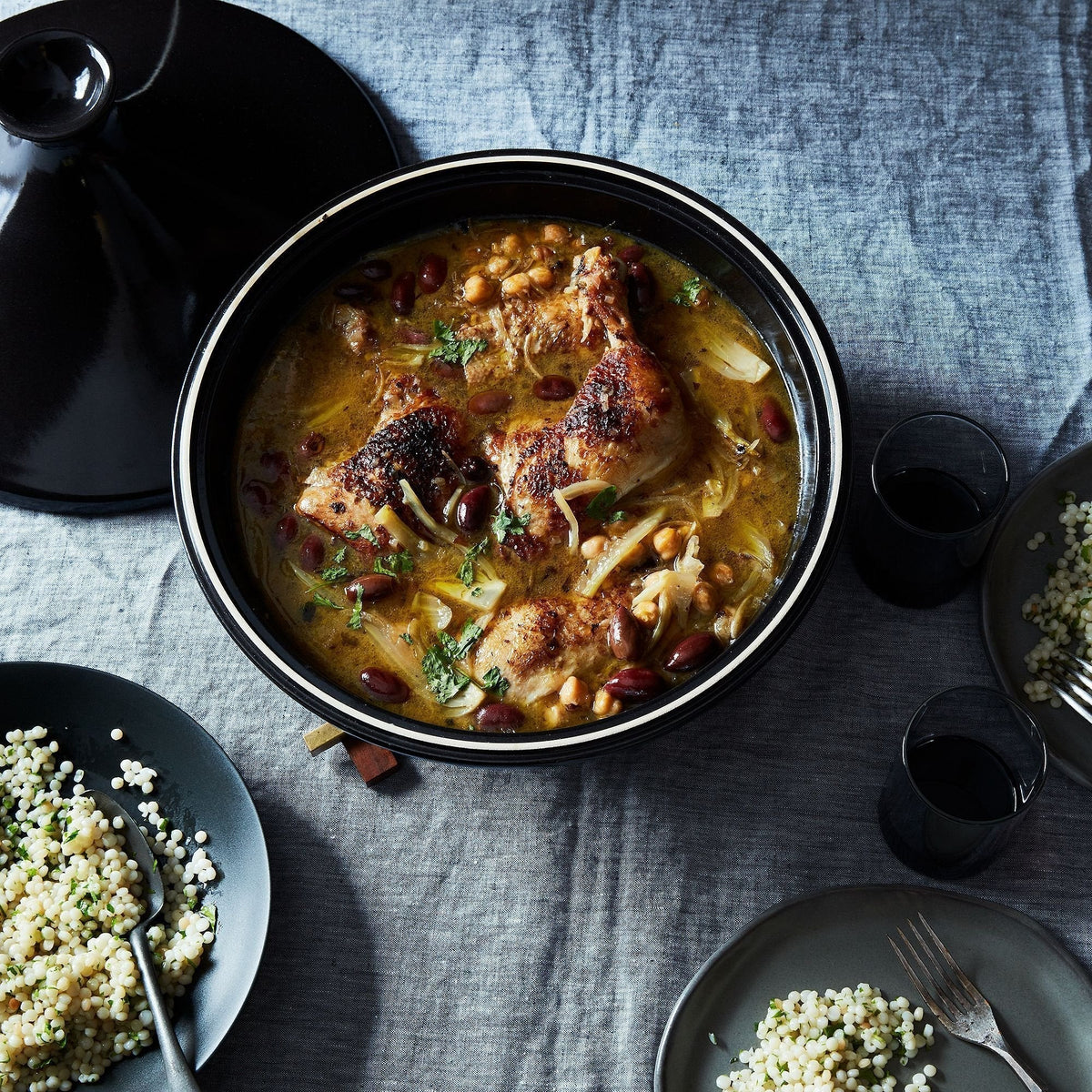 Bowl of chicken and bean tagine stew on a table with side dishes