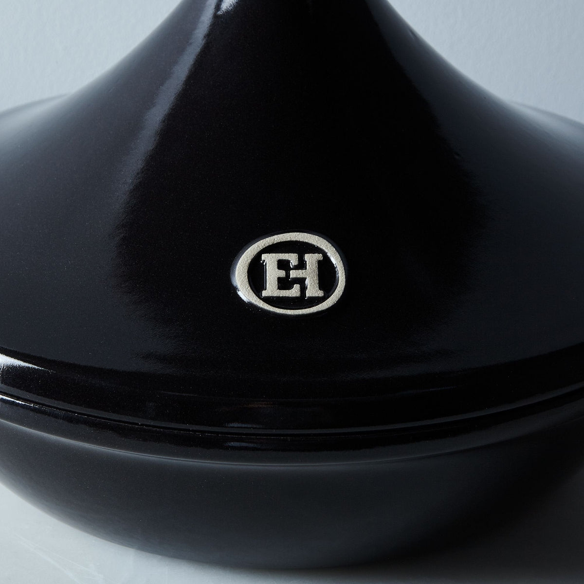 Closeup of black fusain ceramic tagine with a Emile Henry logo on a white background