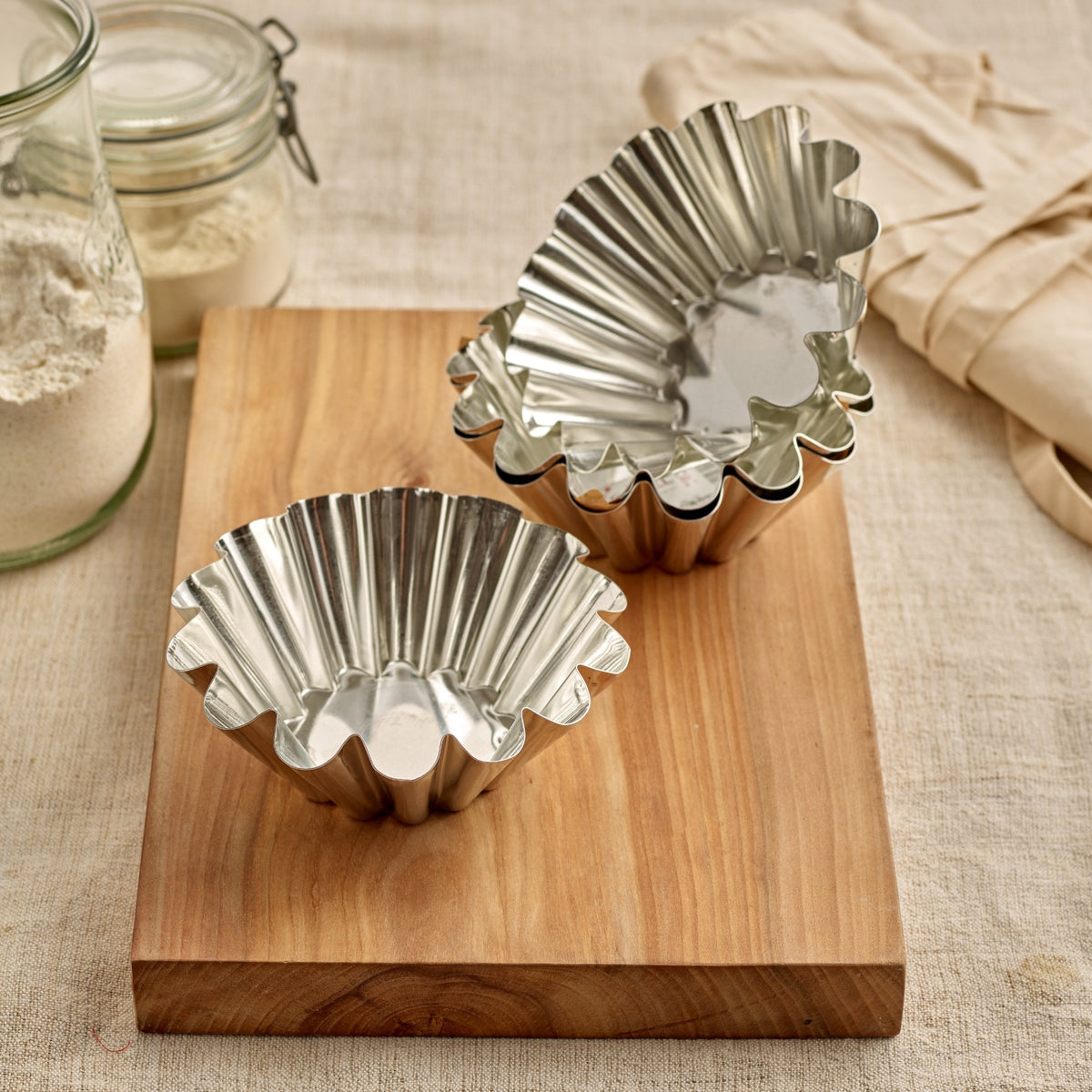 Metal fluted Gobel brioche tinplate mould on a wooden board with jars in the background