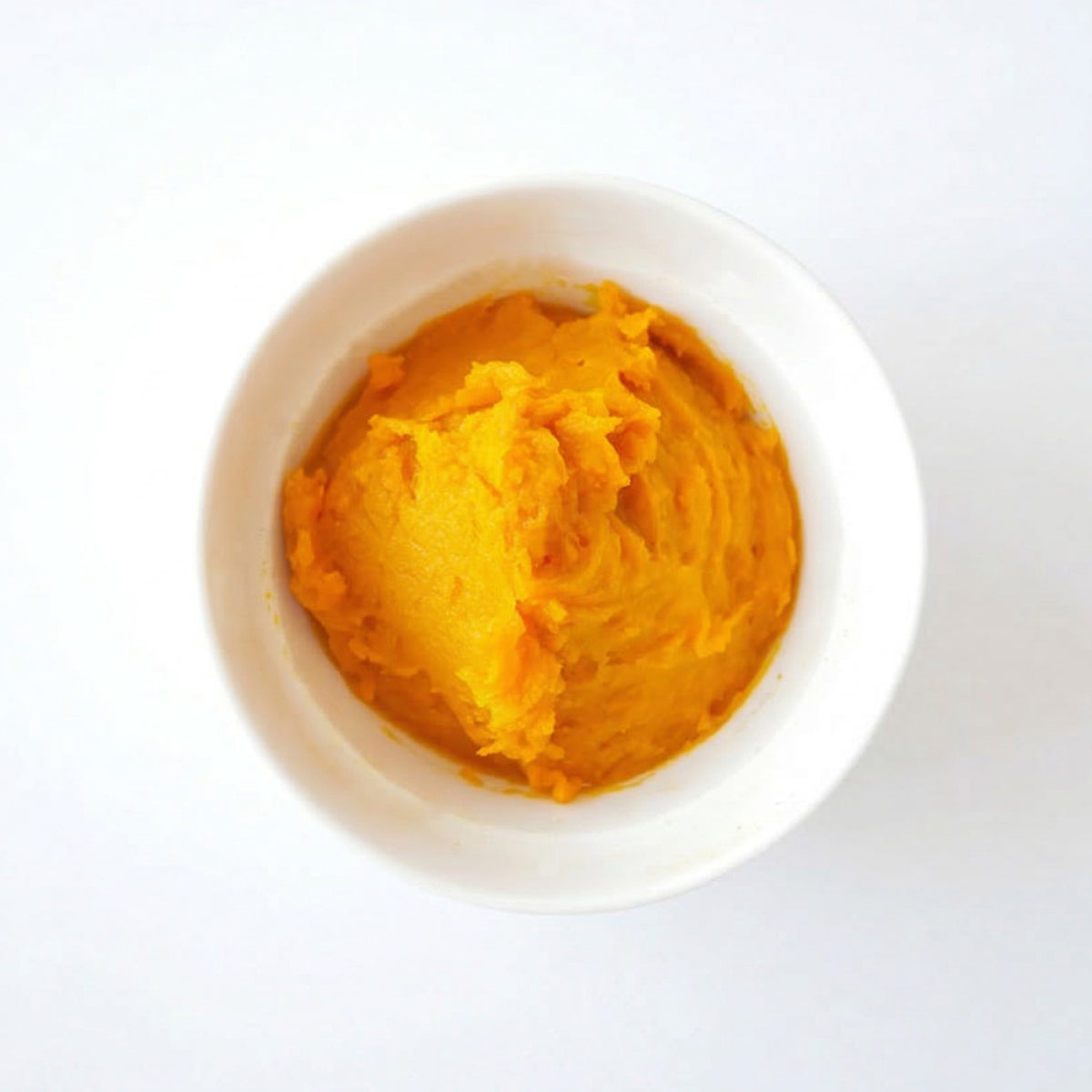 Yellow hokkaido pumpkin puree in a white container on a white background