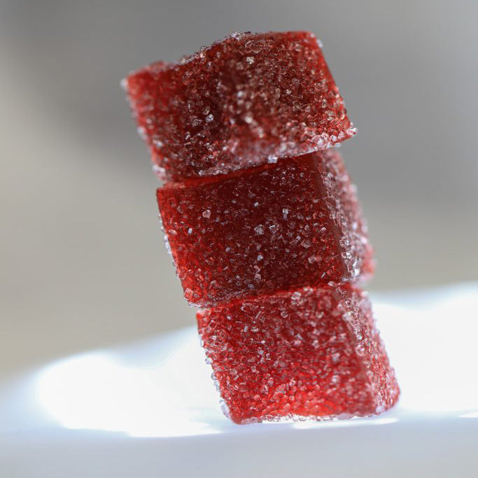 Stack of red gummy bears on a white plate with a blurred background