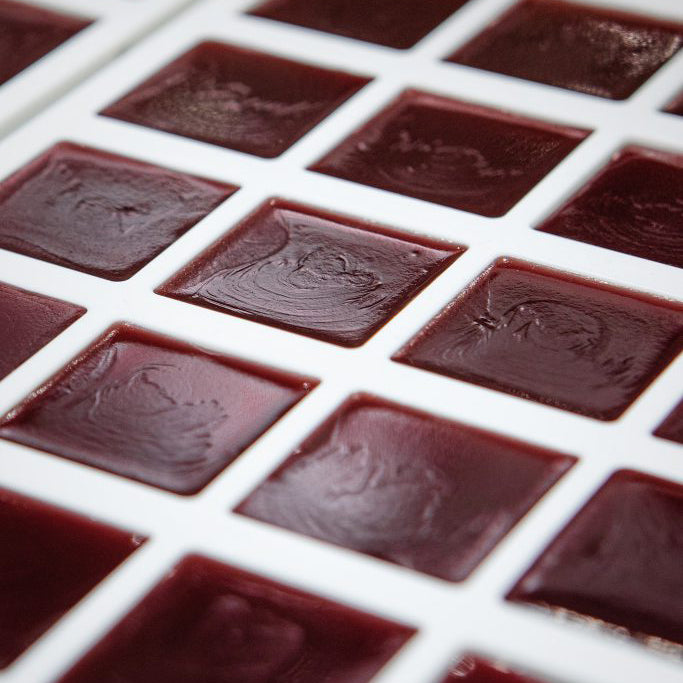 Close-up of a grid of dark red jelly squares on a white background