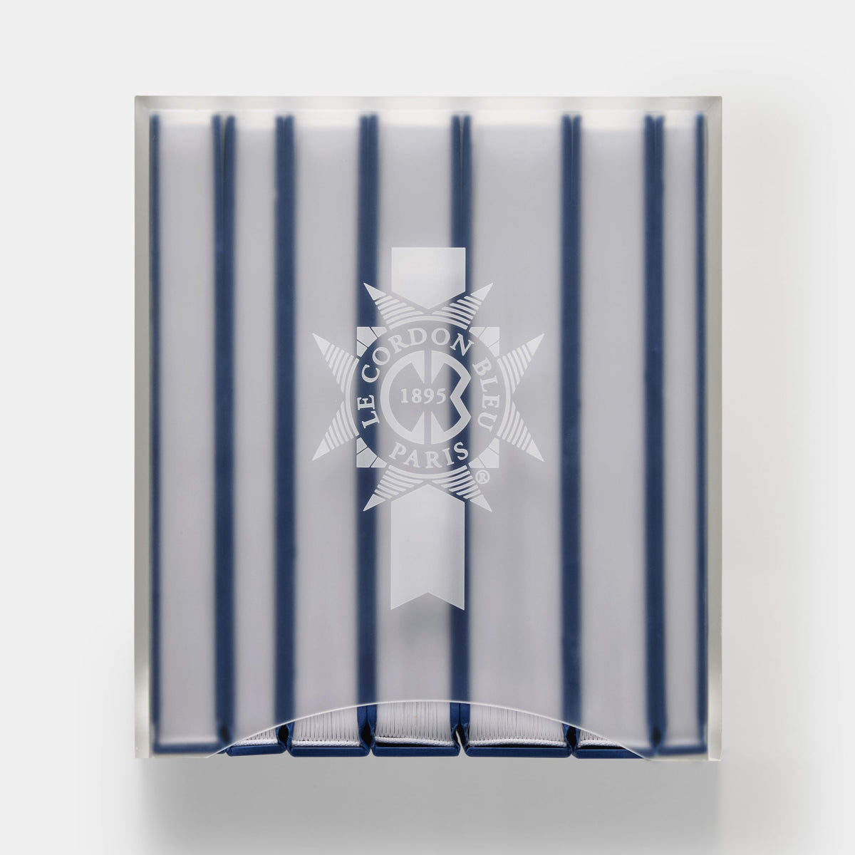 A square clear acrylic block plaque featuring vertical navy blue stripes and a white printed Le Cordon de Paris emblem in the center, shown against a light gray background.
