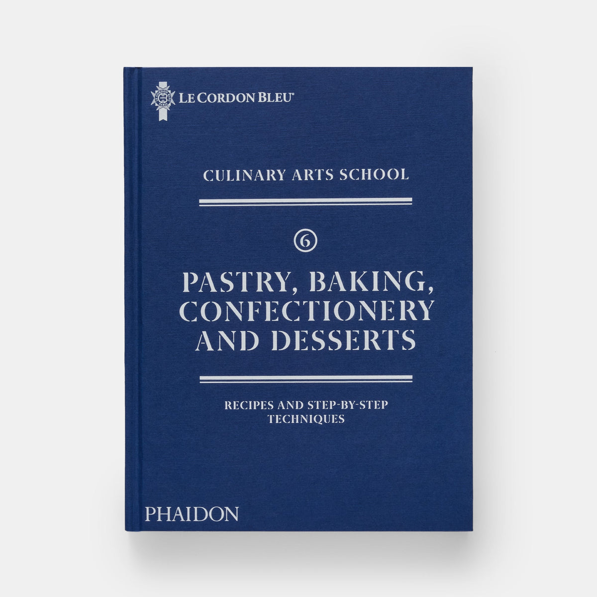 A hardcover book titled 'Pastry, Baking, Confectionery and Desserts' from Le Cordon Bleu Culinary Arts School, published by Phaidon. The book cover is a deep navy blue with white text and decorative lines, set against a clean, light gray background.