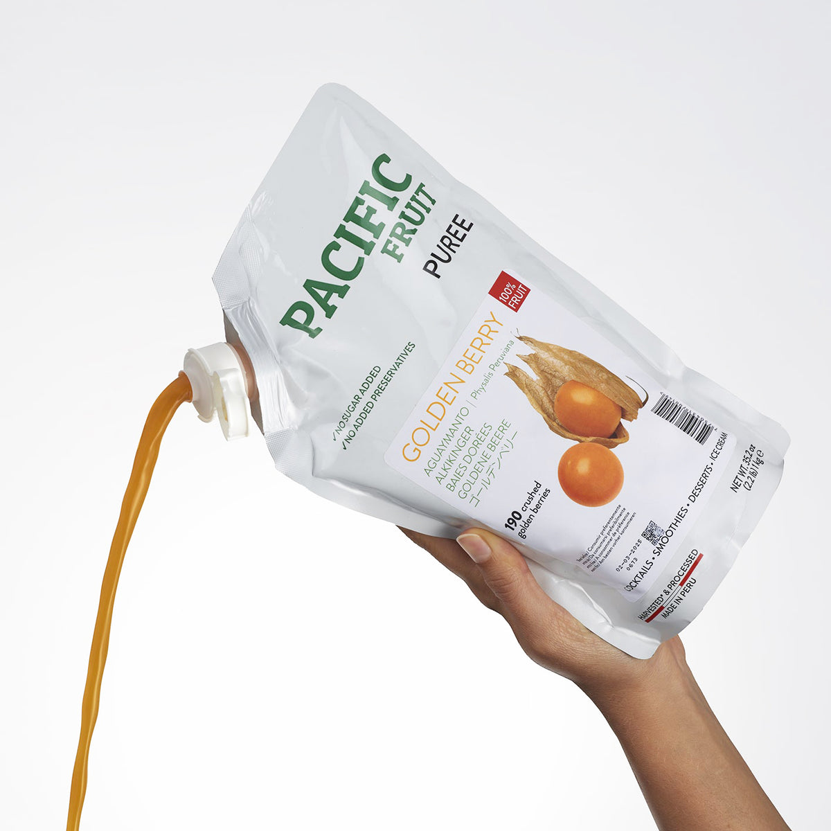 Hand holding a bag of Pacific Fruit Puree with a white background