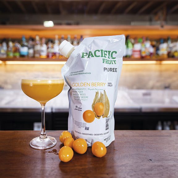Pacific Fruit Puree Golden Berry package with a glass of cocktail and golden berries on a bar counter.