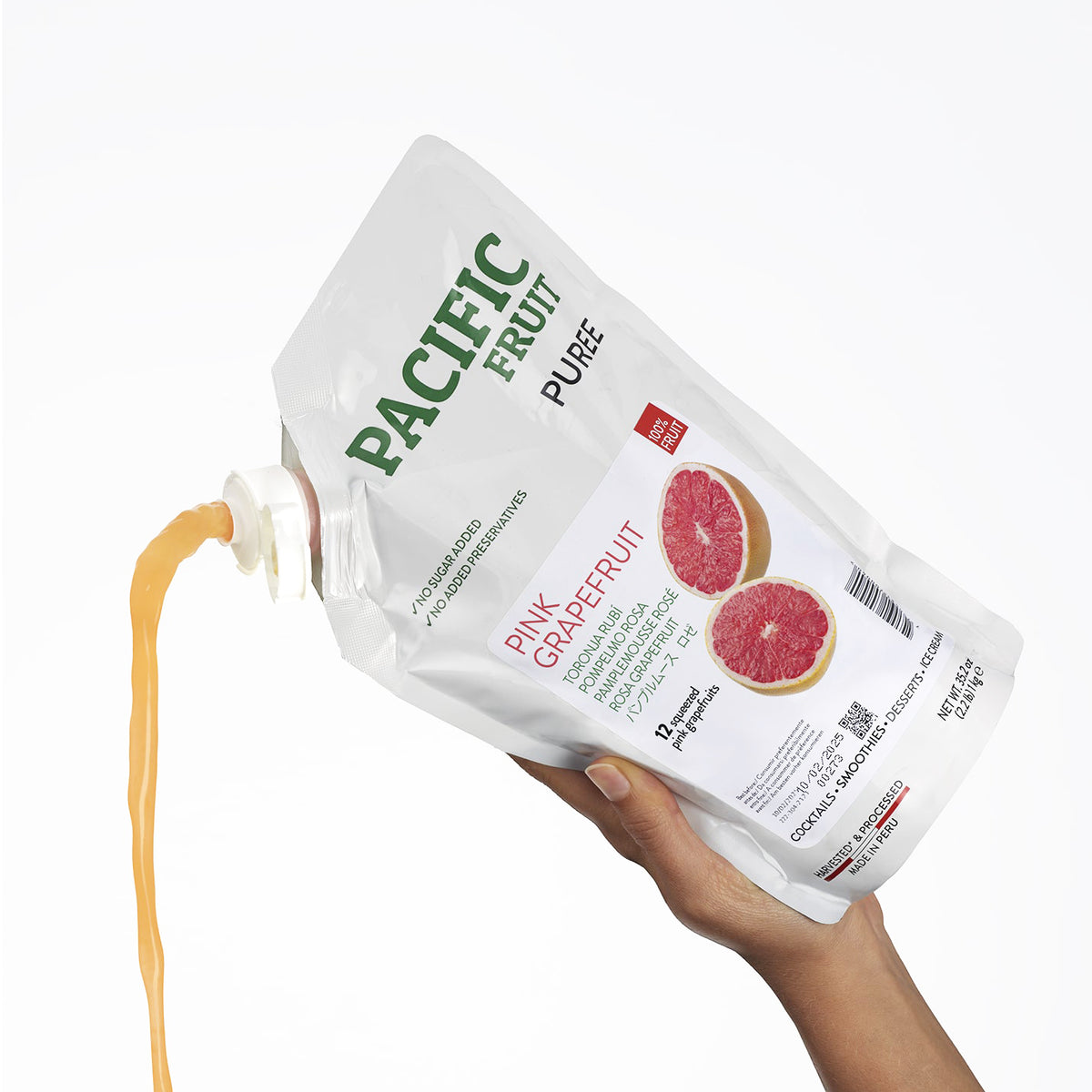 Hand holding a container of Pacific Fruit Shelf Stable Pink Grapefruit Puree with visible label.