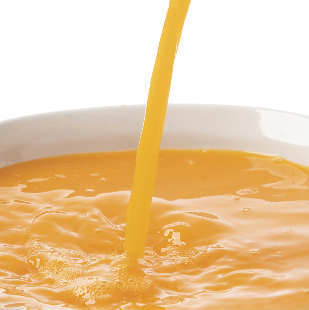 Mandarin juice puree being poured into a white bowl on a white background