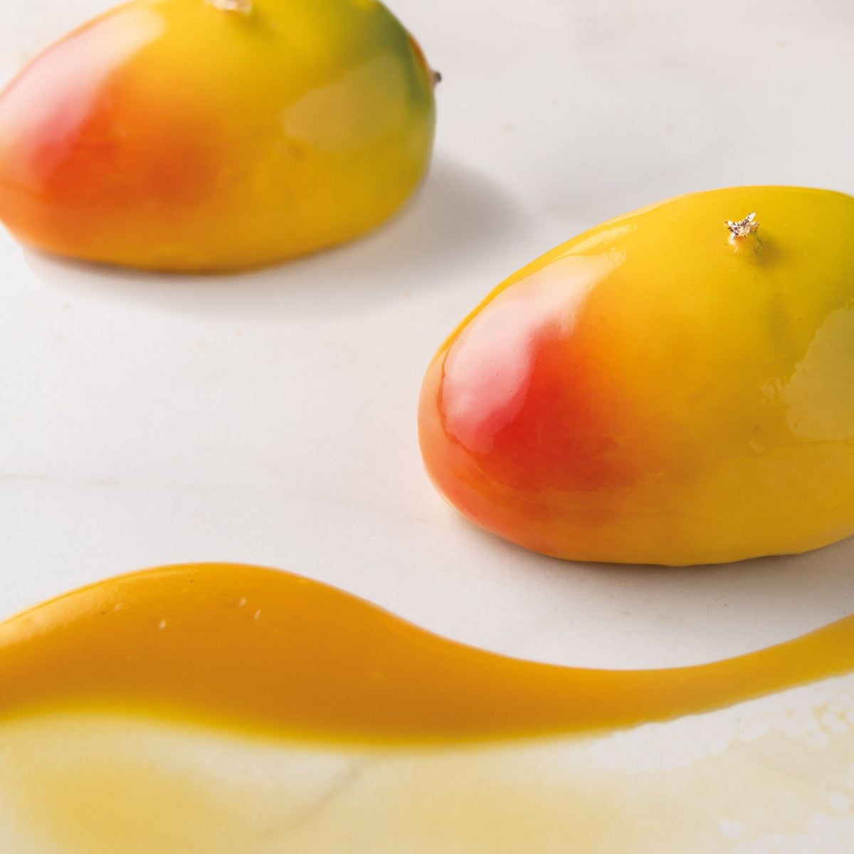 Two mango desserts on a white surface with a close-up of one mango.