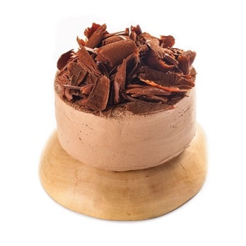 A chocolate cake with light brown frosting and dark chocolate shavings on top, presented on a round wooden plate against a white background.