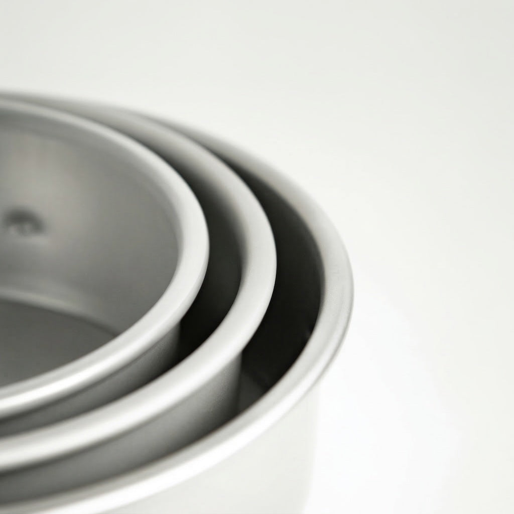 Stack of Sanneng Anodized Deep Round Cake Pan with removable bottom on a light gray background