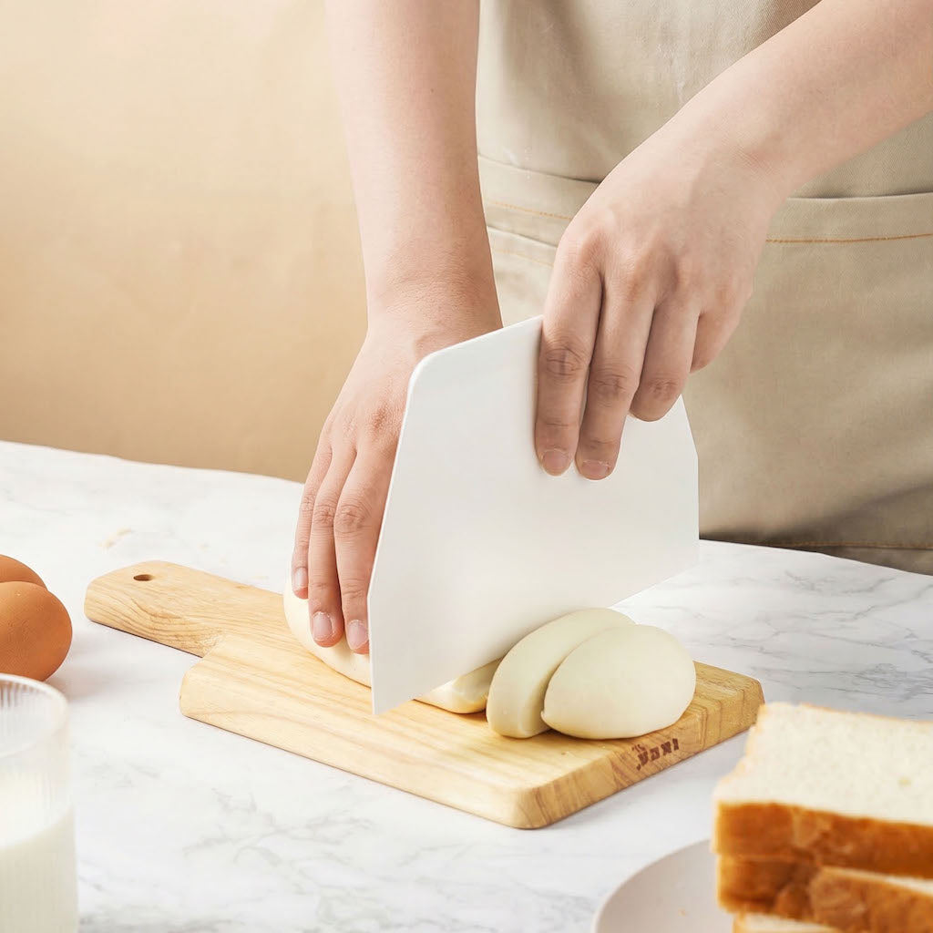 Person slicing bread on a wooden cutting board with a white Sanneng SN4051 scraper