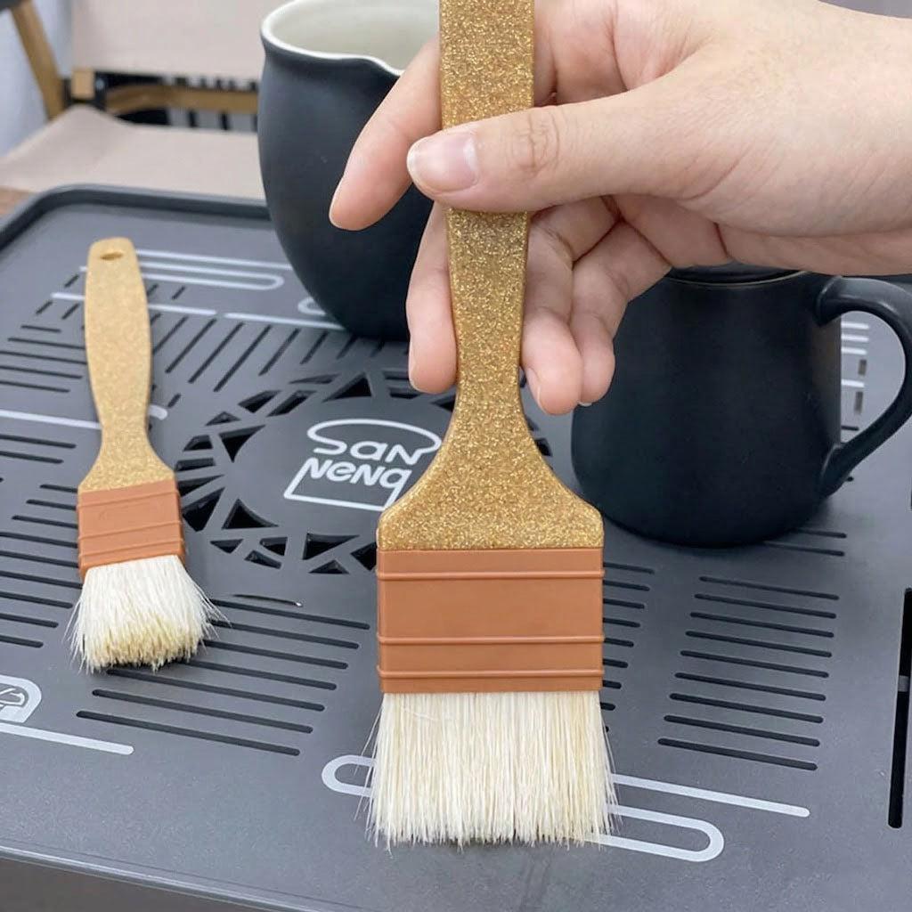Two wooden Sanneng eco handle brushes with bristle heads held by a hand on a black tray with 'Sanneng' branding.