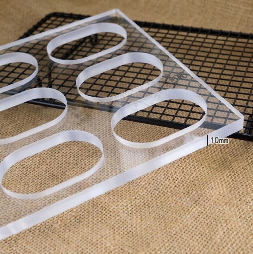 Sanneng Premium Acrylic Dacquoise Template, 12 Oval Cavities on a black mesh grid with a 10mm measurement label on a textured surface.