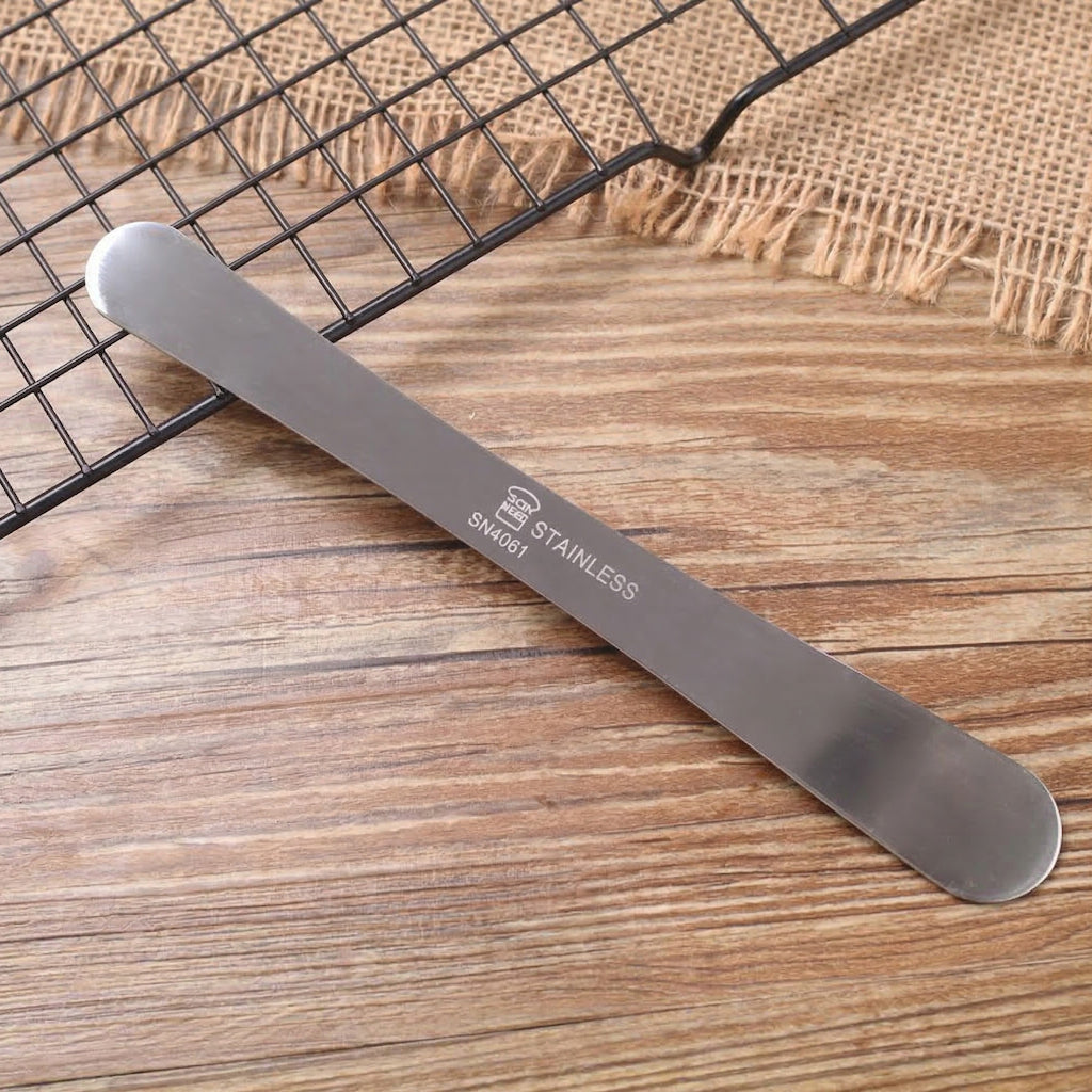 SN4061 Sanneng stainless steel spatula on a wooden surface with a cooling rack in the background
