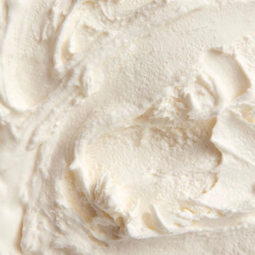 A close-up texture shot of gelato with soft swirls and peaks in a warm off-white color.