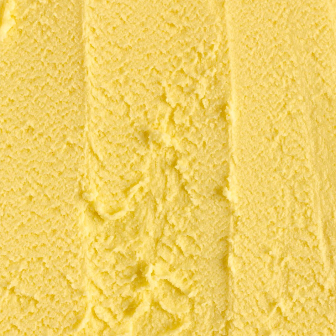 A close-up texture shot of pale yellow gelato with soft vertical ridges and a slightly mottled surface.