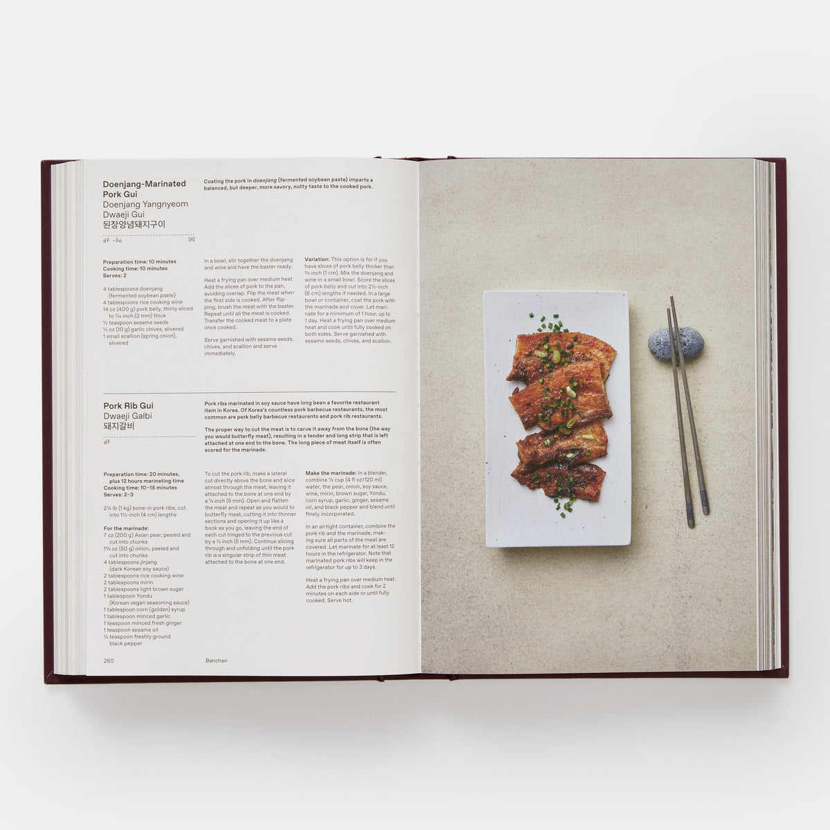 An open cookbook spread showing recipe pages on the left and a food photograph of marinated pork belly on the right, photographed from above on a light gray background.
