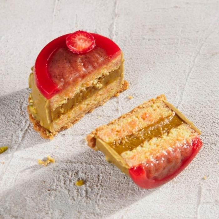Two slices of dessert with red jelly topping on a textured white surface