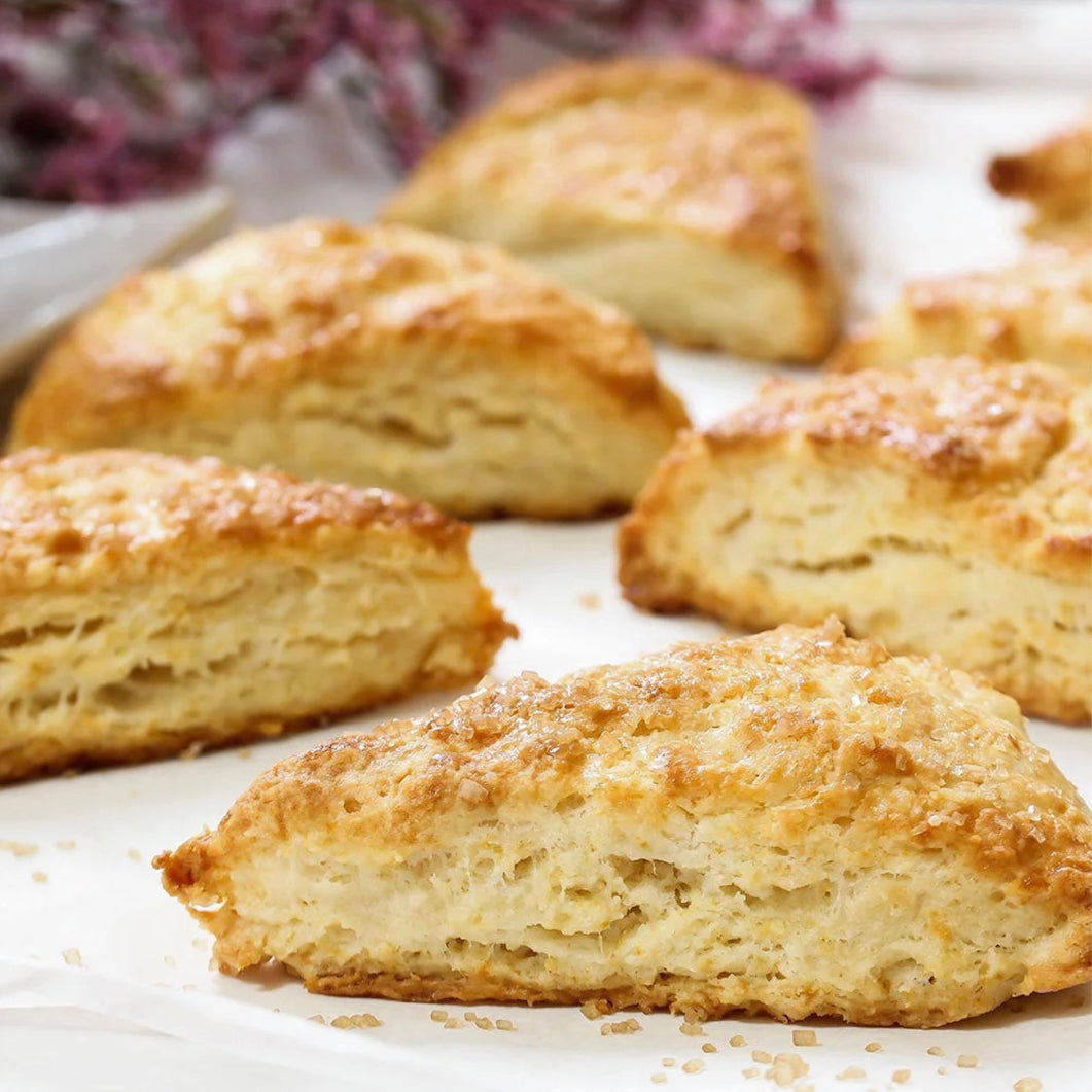 Several golden-brown baked scones arranged on white parchment paper, with a soft blurred background.