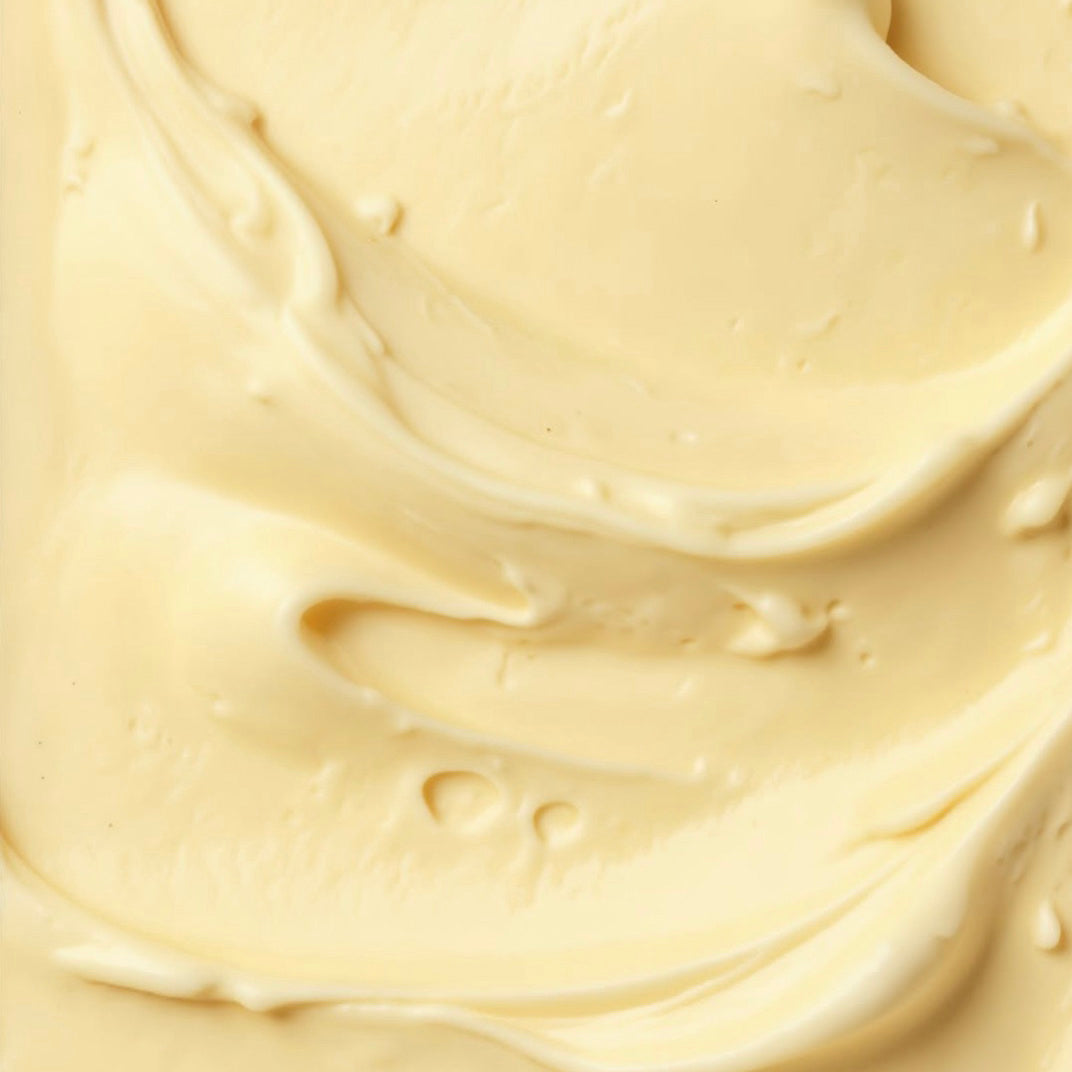 A close-up texture shot of a thick, creamy, pale yellow gelato with smooth swirls and glossy highlights.