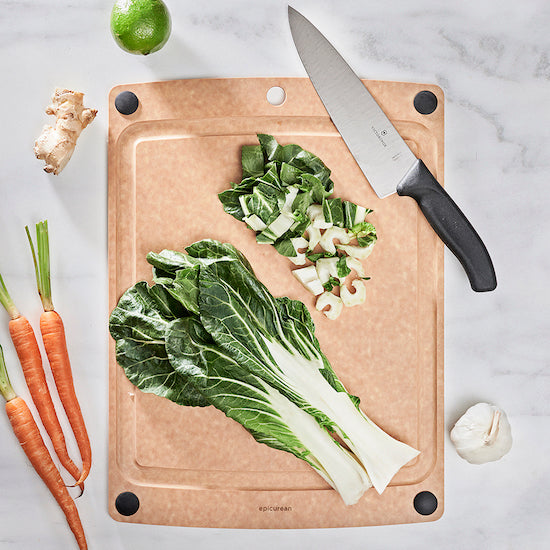 Wooden Epicurean all-in-one series cutting board with chopped vegetables and a knife on a light background