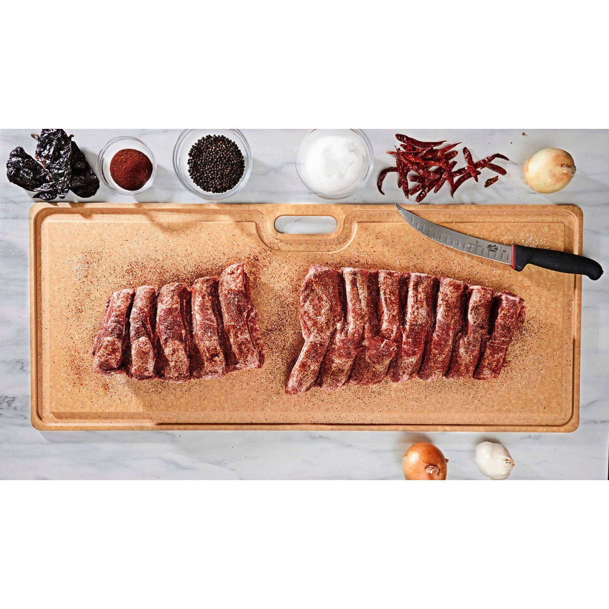 Wooden Epicurean  Big Game Butcher cutting board with sliced meat, spices, and a knife on a white background