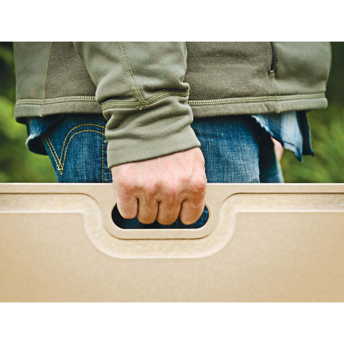 Person holding a Epicurean Butcher cutting board with a blurred green background