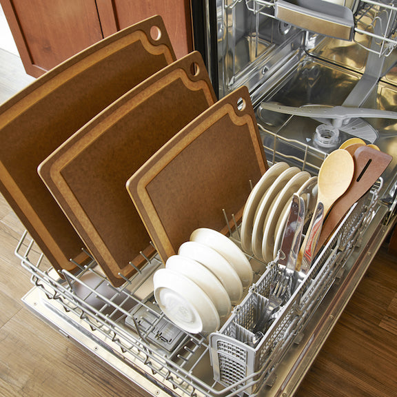 Dishwasher with open door showing clean dishes including Epicurean nutmeg gouremt series cutting boards and utensils.
