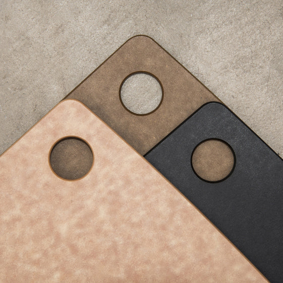 Three rectangular Epicurean kitchen series cutting boards with circular hanging holes on a textured surface