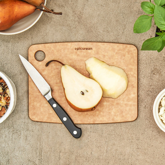 Pears on a Epicurean kitchen cutting board with a knife, on a textured surface.