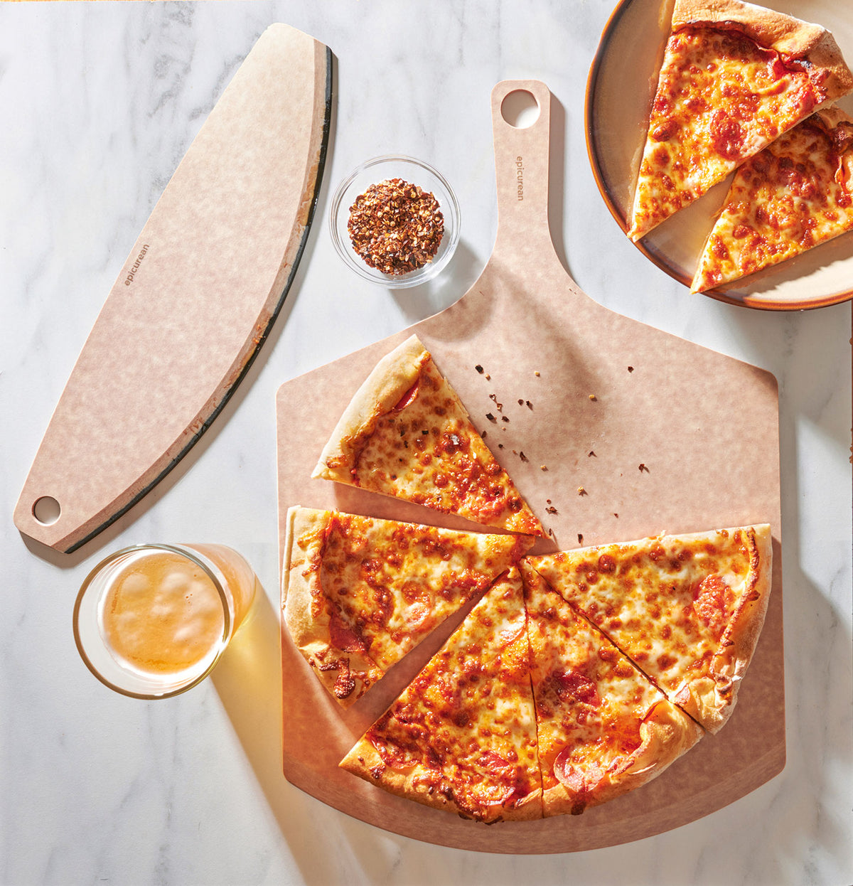 Cheese pizza on an Epicurean pizza peel with a side of sauce, on a marble surface.