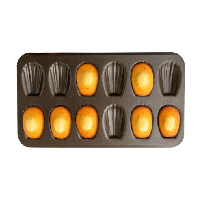 Gobel baking tray with madeleine molds filled with batter on a white background