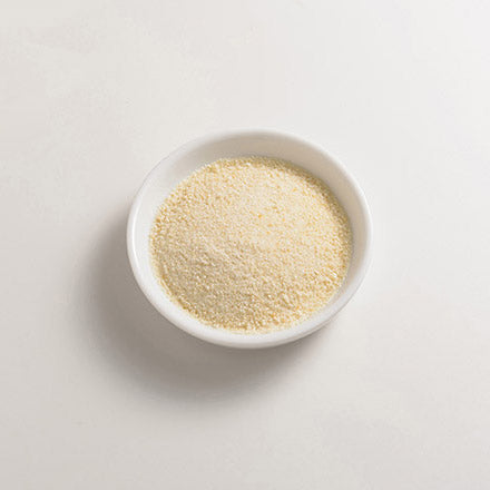 White bowl filled with a light brown yeast powder on a white background