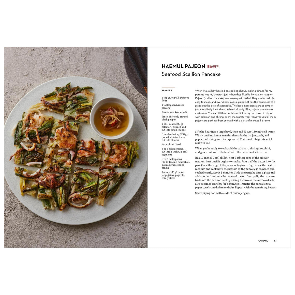 A printed recipe page from a cookbook featuring a photograph of prepared seafood scallion pancakes on a white plate, with the title 'HAEMUL PAJEON' and the dish name 'Seafood Scallion Pancake' plus ingredient and preparation text on the right.