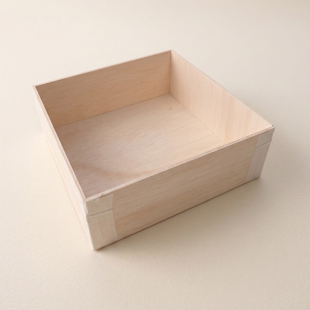 A light natural wood drawer or storage box with a smooth finish, shown from an elevated perspective on a neutral cream-colored background.
