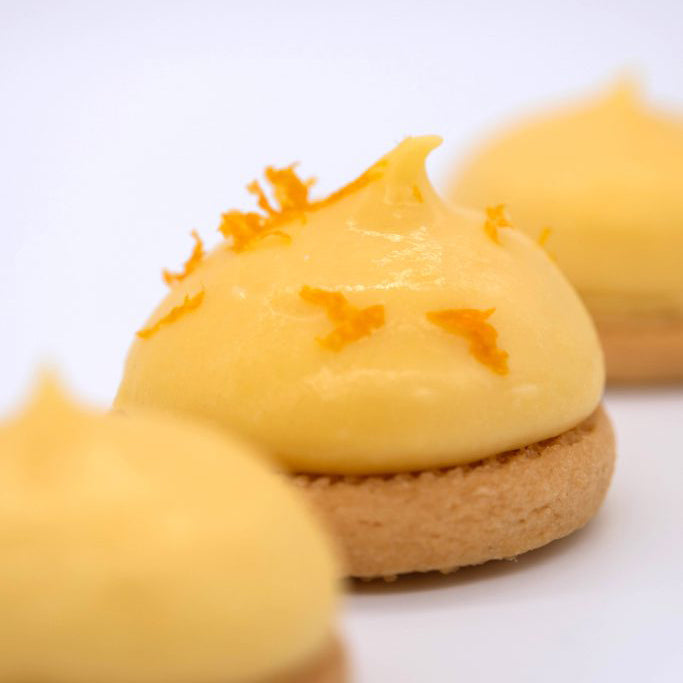 Small dessert with yellow cream and orange zest on a white background