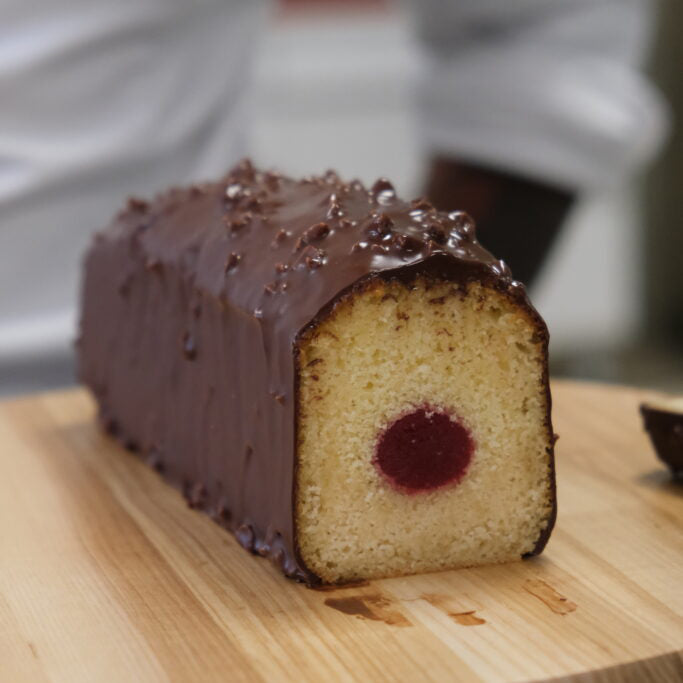 Chocolate frosted cake with a raspberry filling on a wooden board