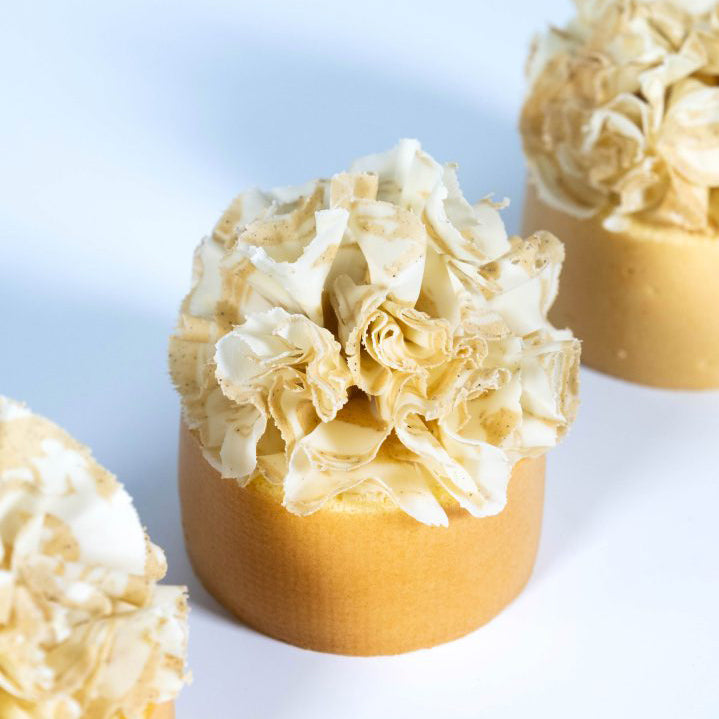 Three cylindrical cakes with floral top designs on a light background