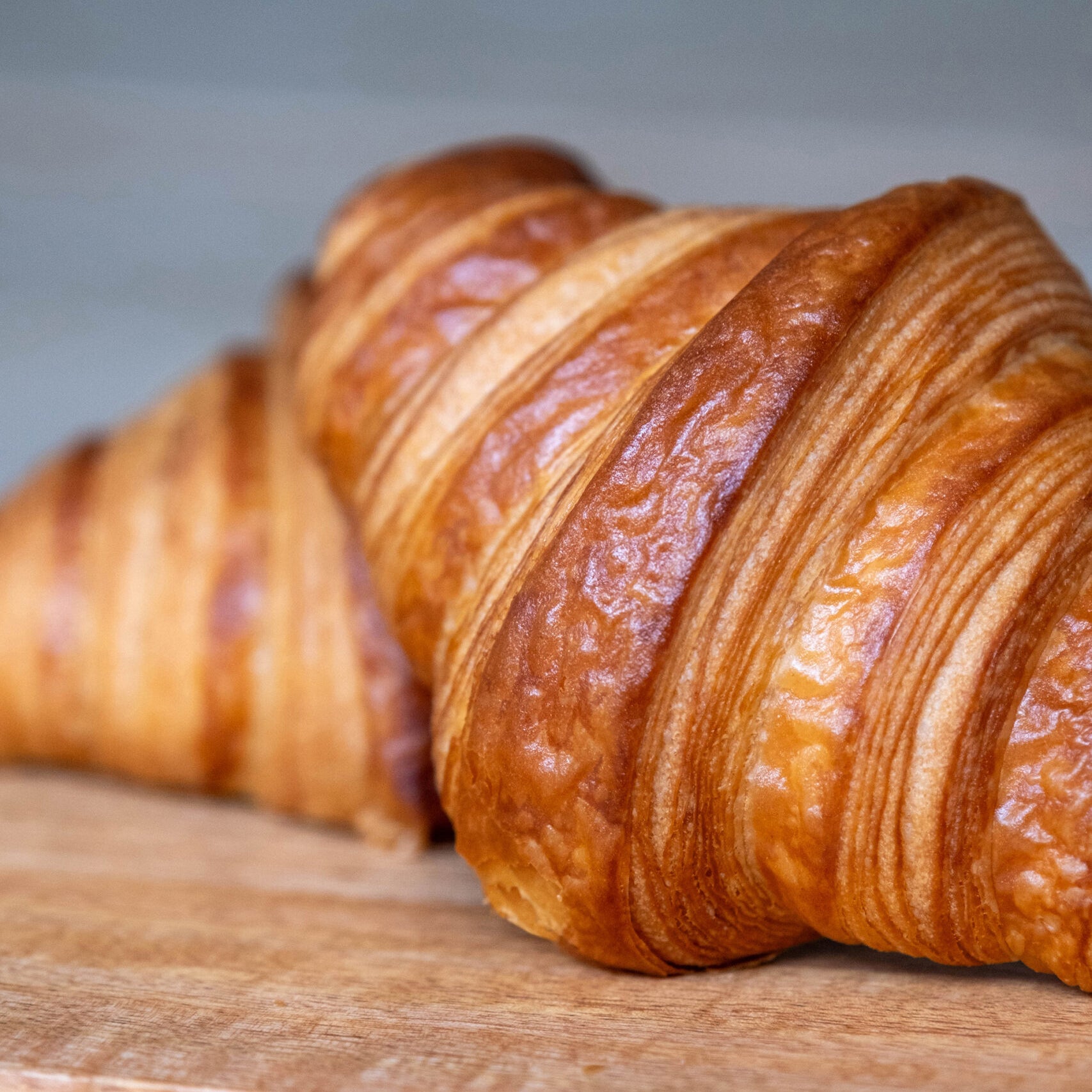 Three croissants on a wooden surface with a neutral background