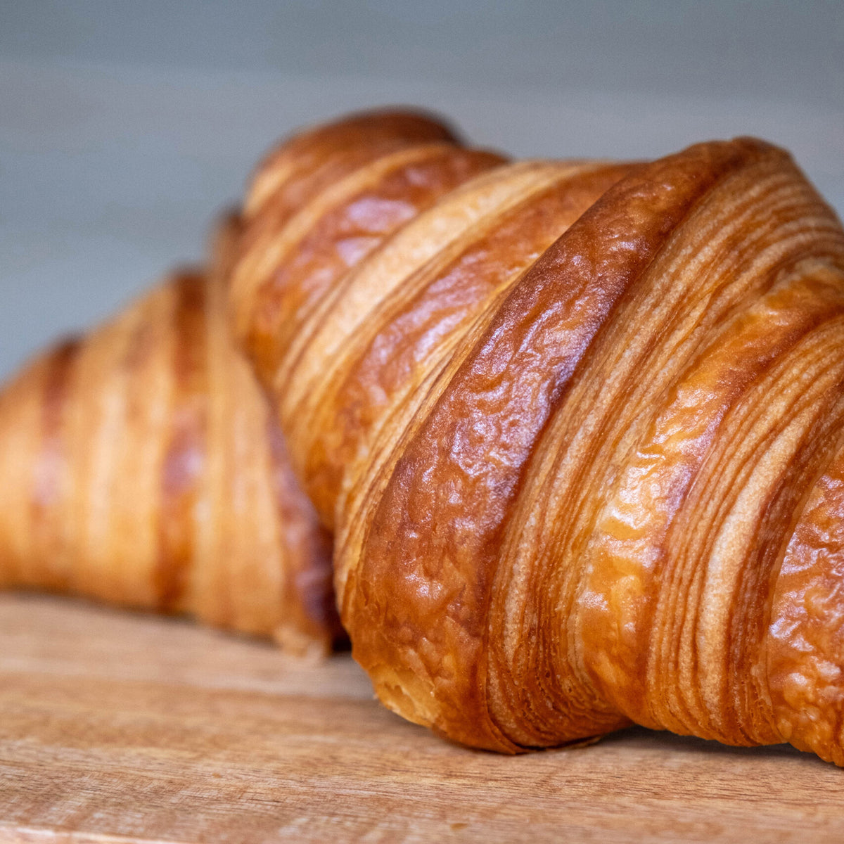 Three croissants on a wooden surface with a neutral background