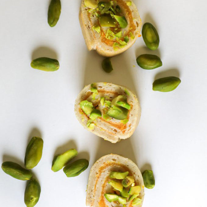 Three sponge rolls with avocado spread on a white surface