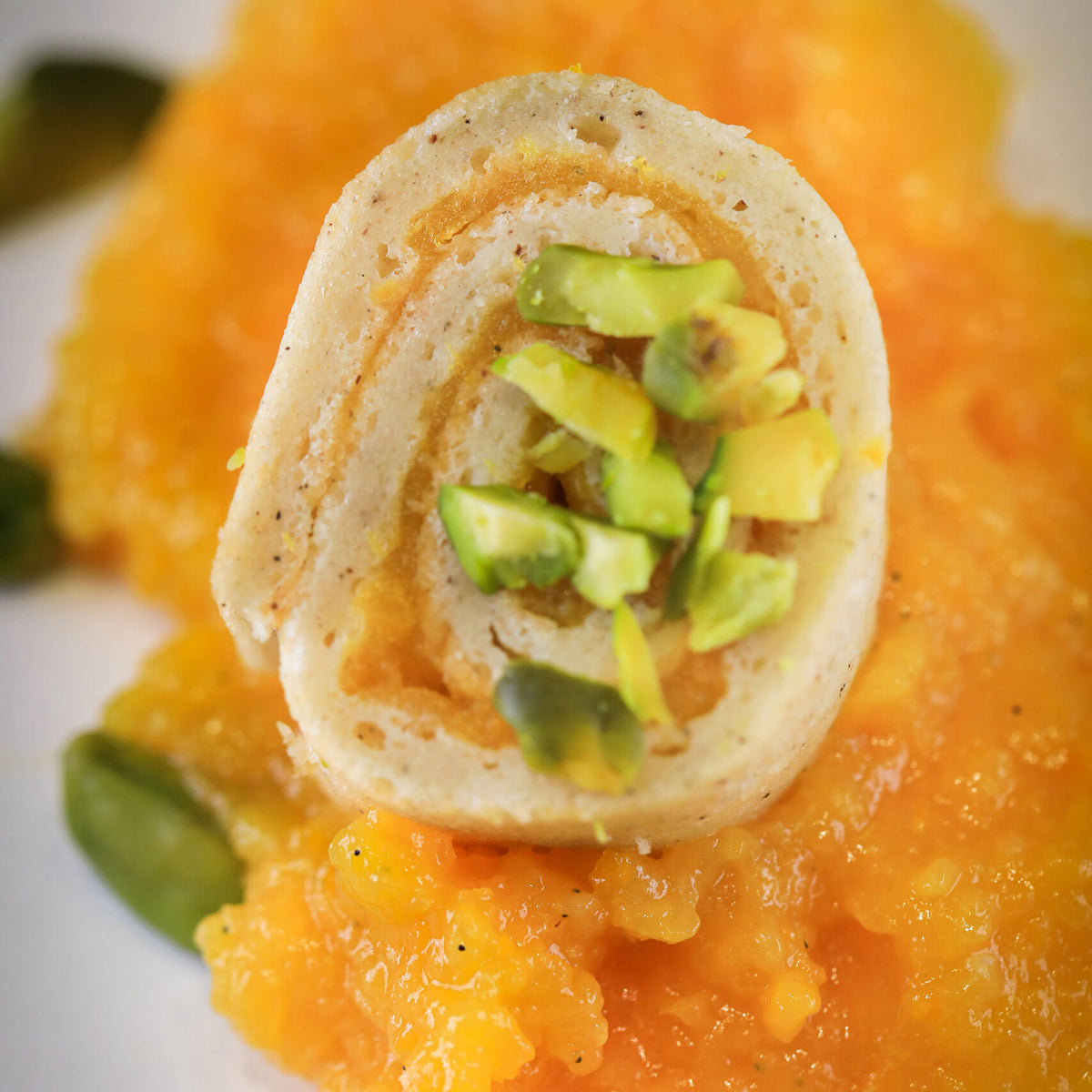 Roll of cake with avocado on a bed of orange puree