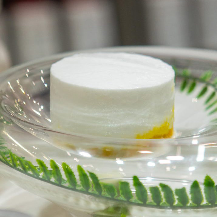 White panna cotta on a decorative glass plate with green leaf patterns
