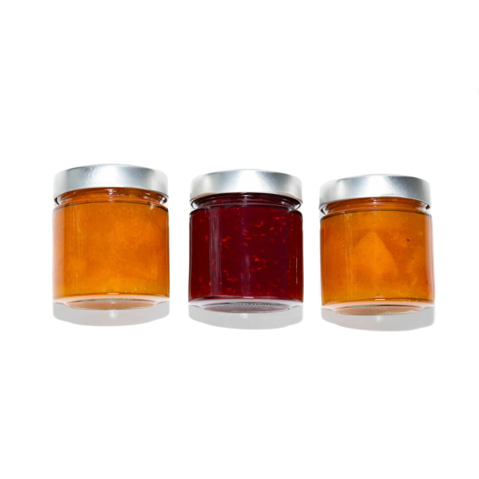 Three jars of different types of jam on a white background