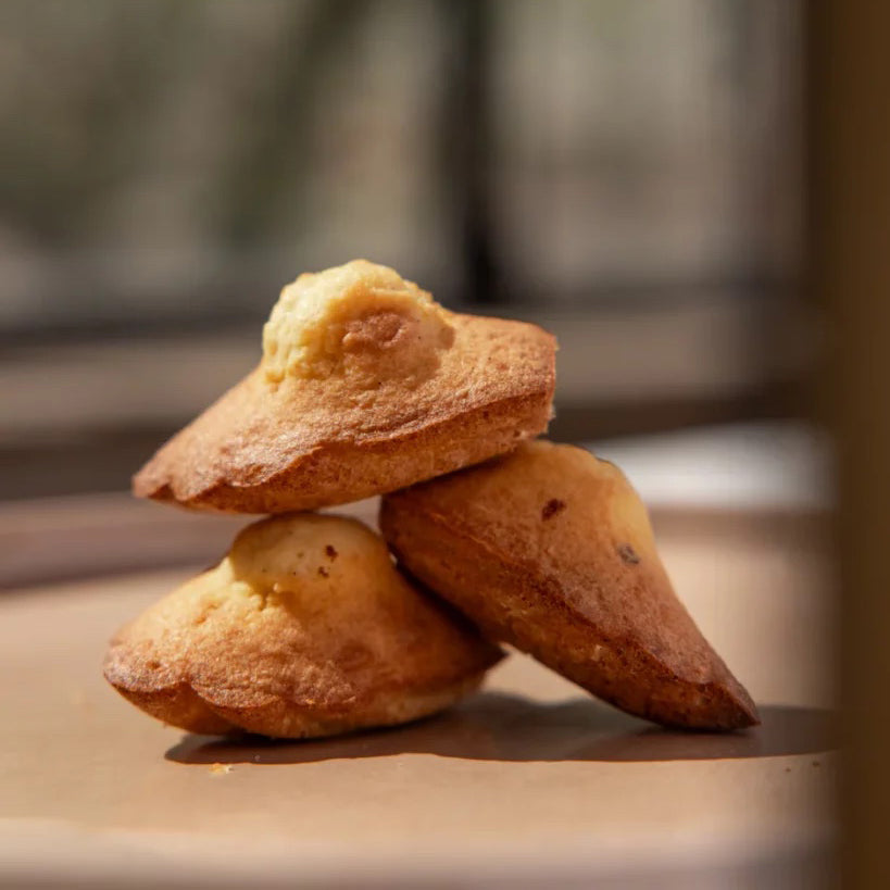 Three small baked pastries stacked on a wooden surface with a blurred background