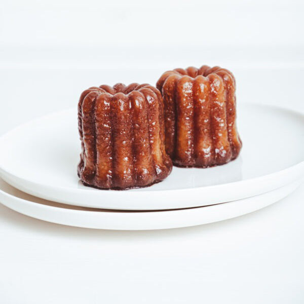 Two small brown cakes on a white plate with a white background