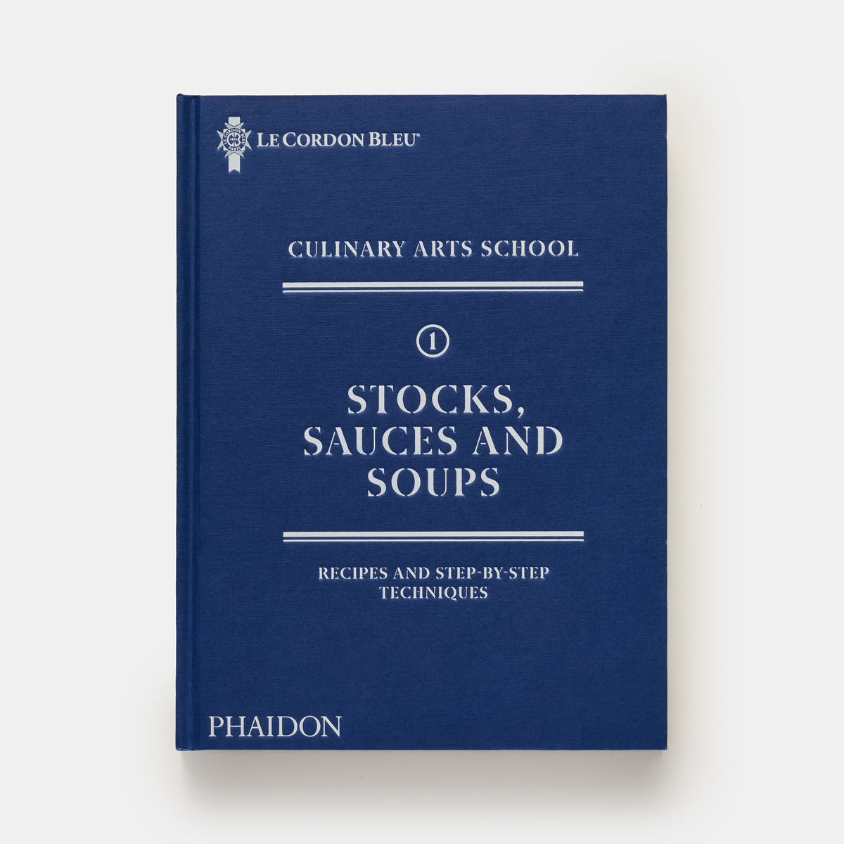 A hardcover book titled "Stocks, Sauces and Soups" from Le Cordon Bleu Culinary Arts School, published by Phaidon. The book cover is a deep navy blue with white text and decorative horizontal lines, set against a clean white background.