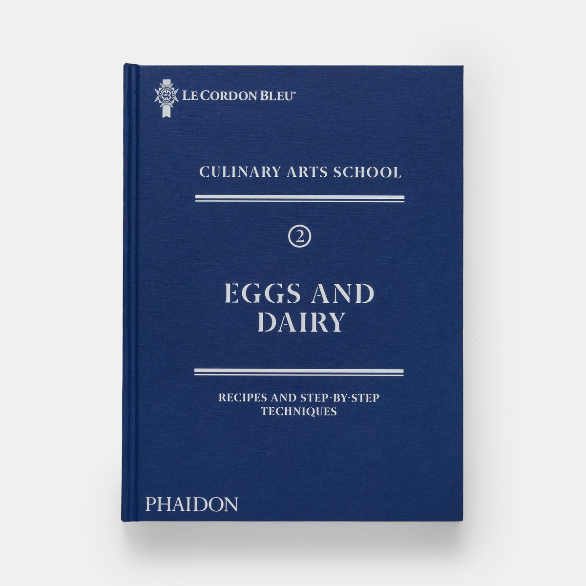 Blue book titled 'Eggs and Dairy' from Le Cordon Bleu Culinary Arts School on a white background